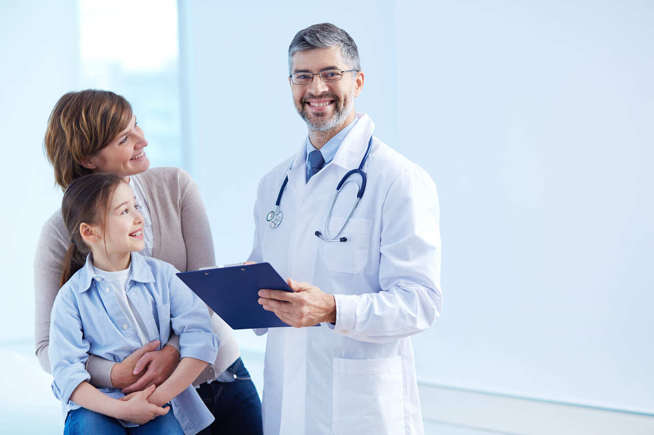 Médico posa sorridente durante atendimento a pacientes 