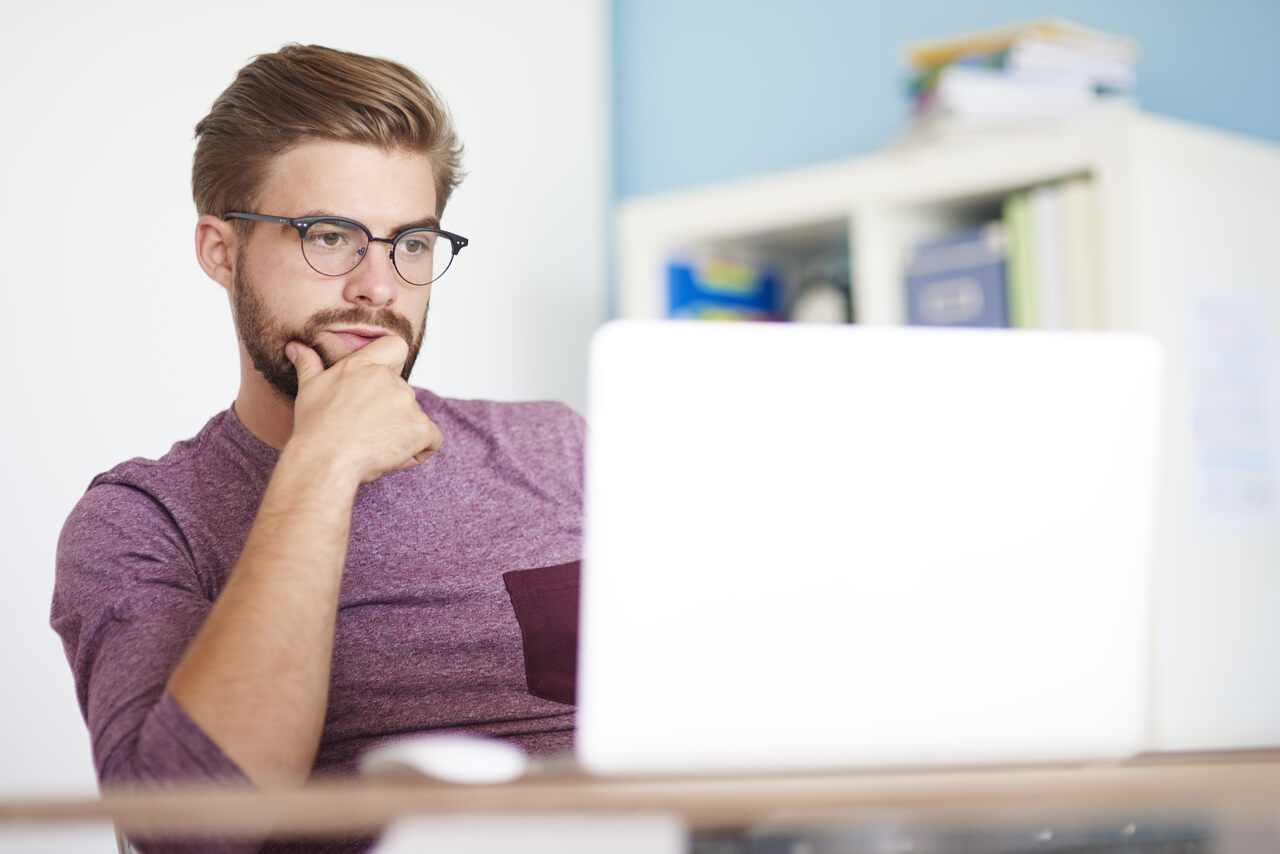 Homem trabalha em seu notebook em sua frente 