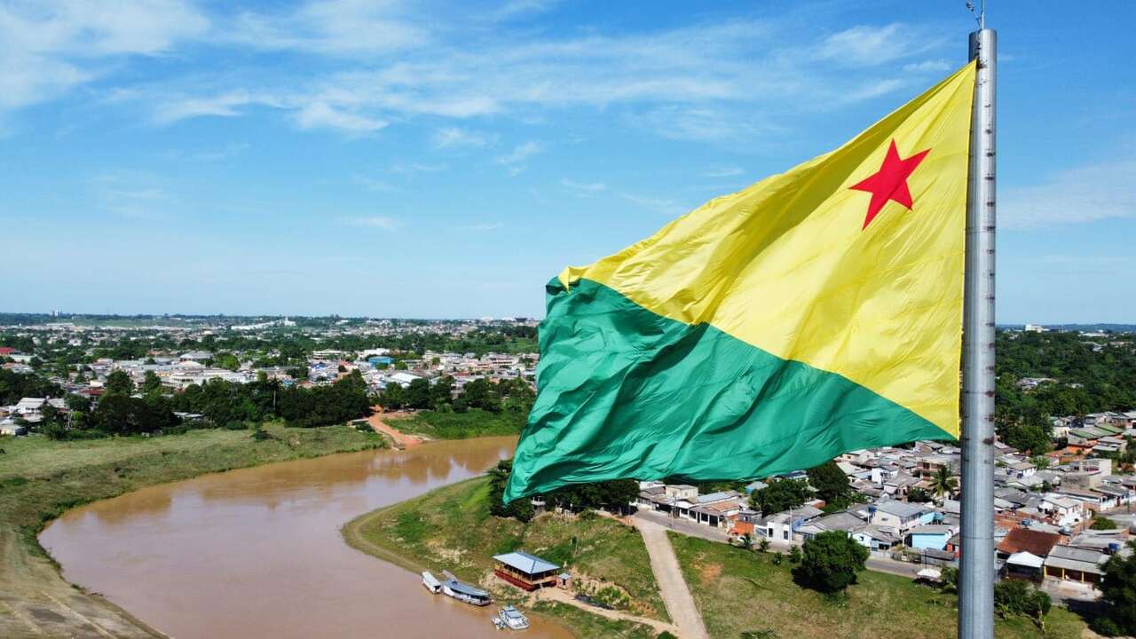 Vista de parte de uma cidade do Acre com bandeira do estado em primeiro plano