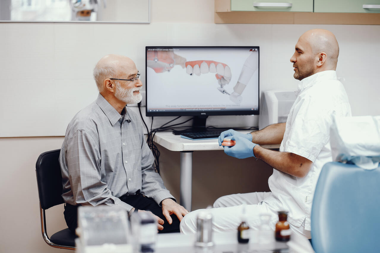 Dentista conversa com paciente sobre possibilidade de próteses dentárias 