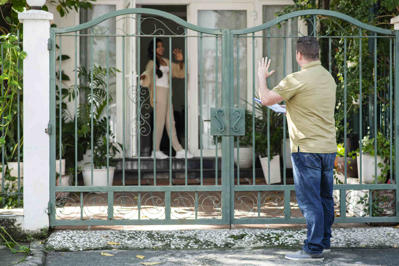 Mulher atende funcionário do Censo em seu portão 