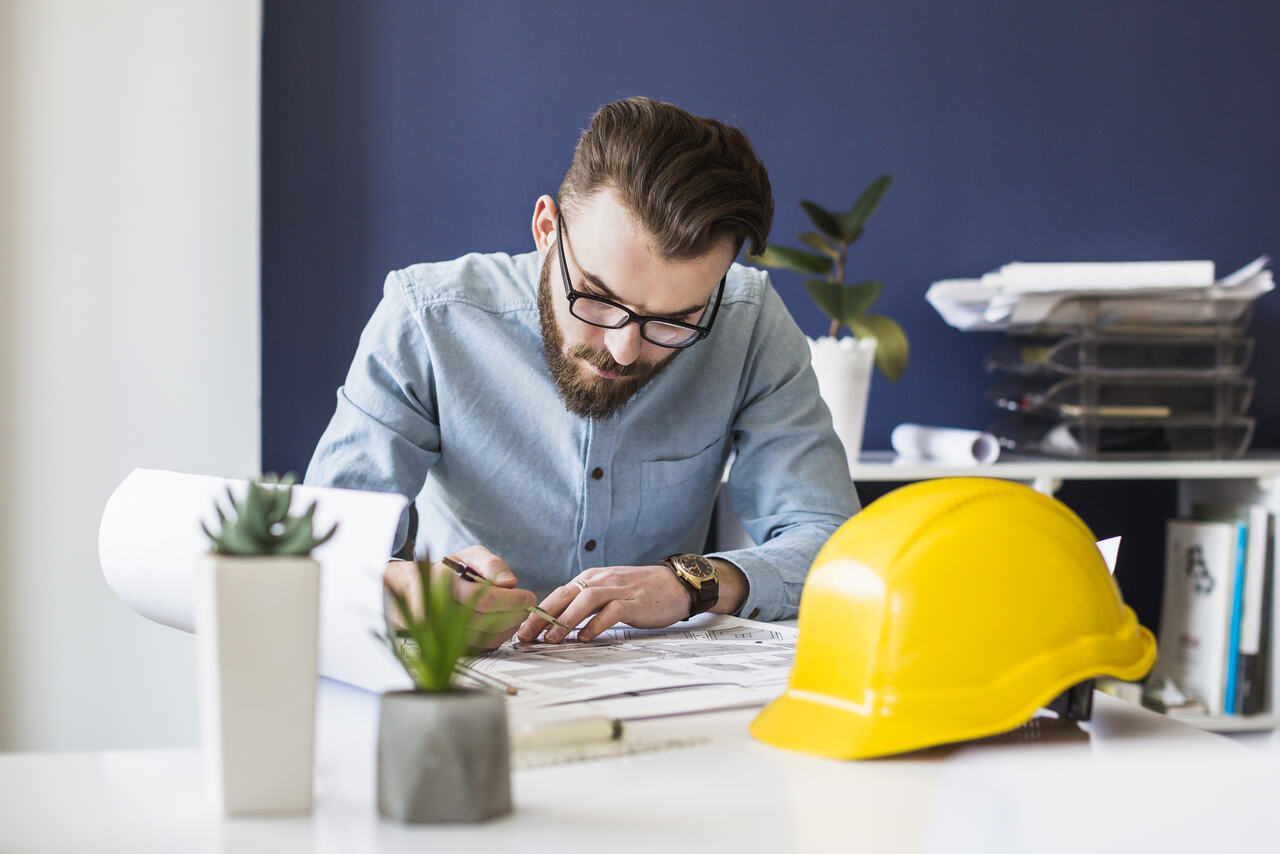 Engenheiro trabalha em projeto em sua mesa 