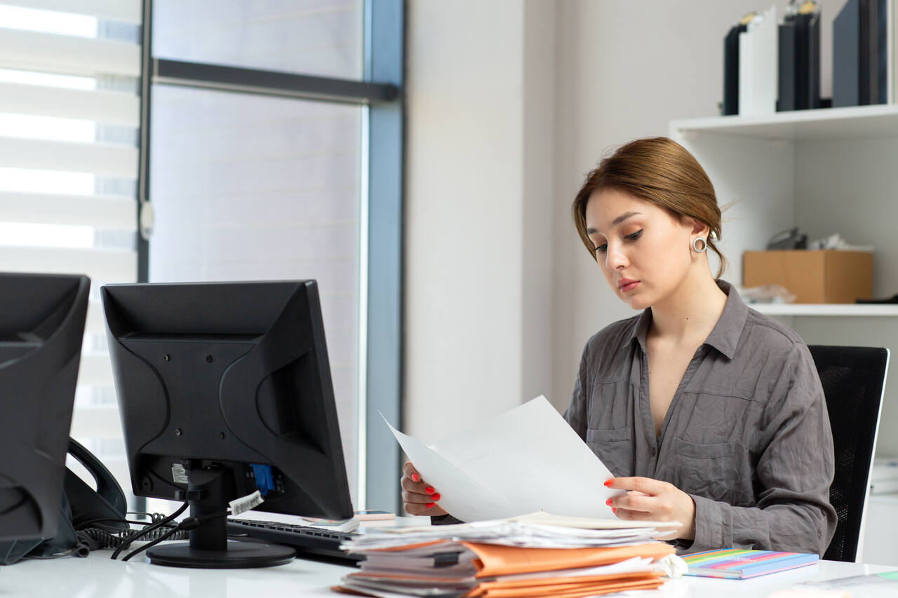 Profissional analisa documentos sentada em sua mesa de trabalho 